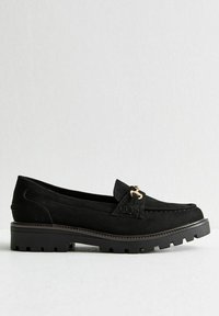 Svart mocka loafer-sko med en dekorativ guldfärgade hårdvarudetalj, som har en tjock gummisula och en texturerad sömdetalj.