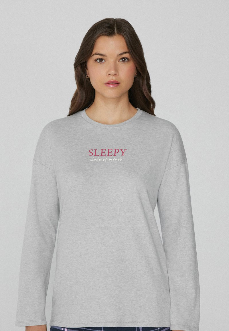 Camisa de manga larga gris hecha de un tejido suave que presenta la palabra "SLEEPY" en rosa y "state of mind" en un texto más pequeño debajo. Diseño simple y relajado.
