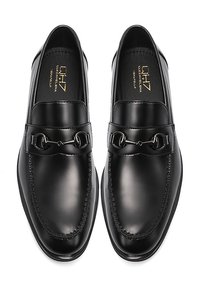 Mocassini in pelle nera con finitura lucida, caratterizzati da una cucitura e un dettaglio decorativo a fibbia nella parte superiore.