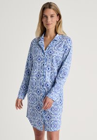 Abito camicia azzurro chiaro con un motivo geometrico in blu scuro. Maniche lunghe, colletto, chiusura frontale con bottoni e dettaglio con spacco laterale. Tessuto morbido.