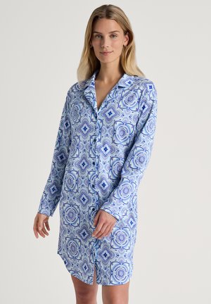 Abito camicia azzurro chiaro con un motivo geometrico in blu scuro. Maniche lunghe, colletto, chiusura frontale con bottoni e dettaglio con spacco laterale. Tessuto morbido.