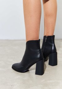 Black ankle boots with a smooth leather finish, featuring a square block heel and a side zipper closure. Simple, streamlined design.