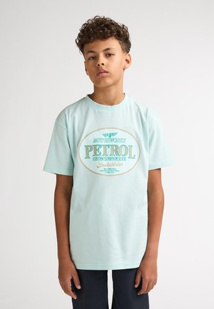 Lyseblå bomuld T-shirt med korte ærmer, med en vintage-stil benzinlogo i grøn og beige. Glat tekstur, afslappet pasform.