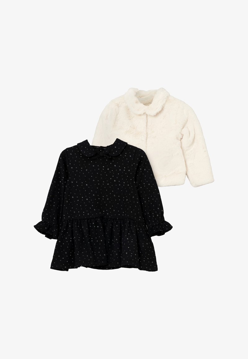 Schwarzes Kleid mit langen Ärmeln, kleinen weißen Sternmustern und einem Rüschensaum, kombiniert mit einer weißen Kunstpelzjacke mit rundem Kragen.