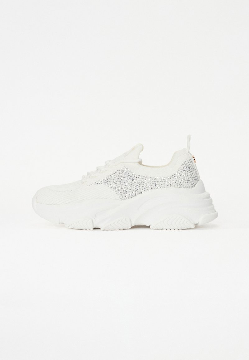 White athletic sneaker featuring a textured upper with sparkling accents, thick sole, and reinforced heel tab for support.