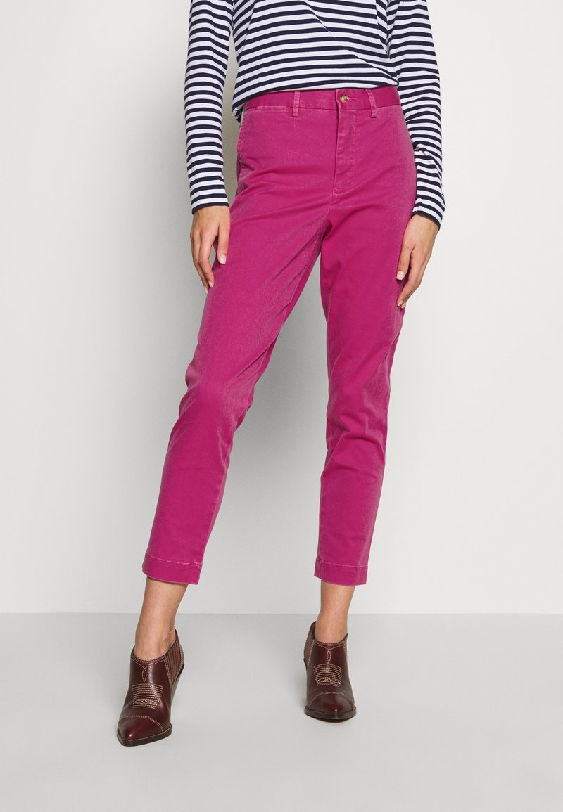 Pantaloni di cotone rosa con vestibilità dritta e orlo a risvolto. Abbinati a una maglietta a righe navy e bianca a maniche lunghe e scarpe con tacco marroni.