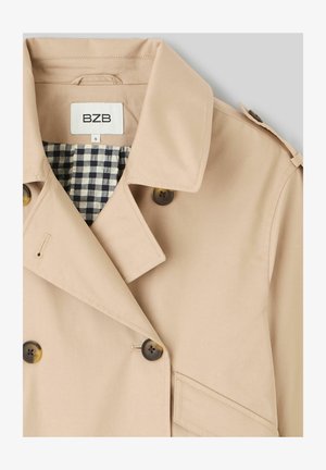 Trench-coat beige à boutons croisés, doublure intérieure à carreaux noirs et blancs, épaulette sur l'épaule et col avec l'étiquette de la marque BZB.