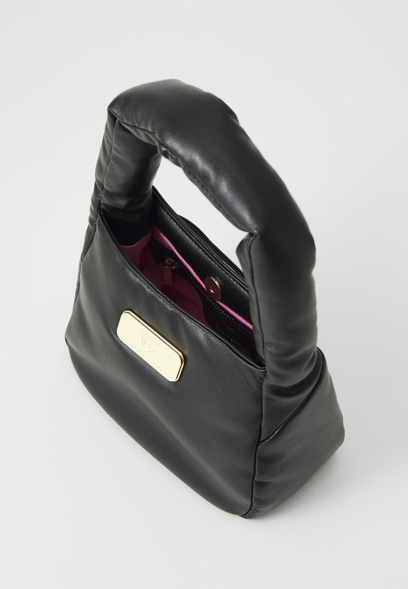 Sac à main en cuir noir avec une poignée rembourrée, des accessoires en or et un intérieur rose. Il comporte une poche zippée et un devant plat avec une plaque logo.
