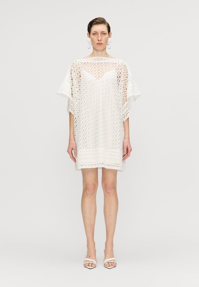 Rochie albă din dantelă, cu croială lejeră, decolteu în V și mâneci până la cot,decorate cu detalii ornamentale și modele decupate.