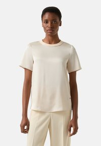 Lichtbeige shirt met korte mouwen en een ronde hals, gemaakt van gladde stof, met een rechte snit en subtiele zijsplitten aan de zoom.