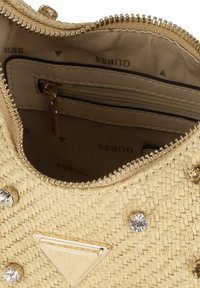 Geweven rieten handtas in beige met gouden hardware, ritssluiting en decoratieve strassstenen. Binnenin is er een ritsvak.