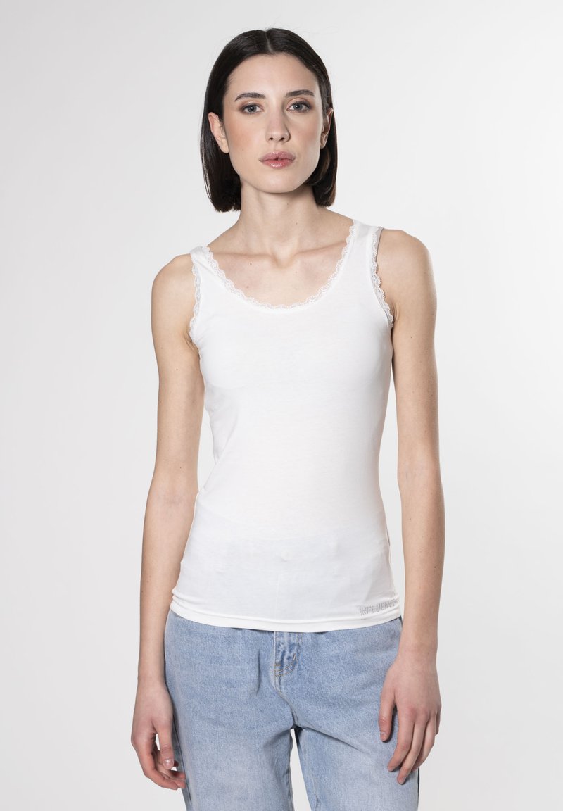 Weißes Tanktop mit Spitzenbesatz am Ausschnitt und den Trägern, aus einem glatten, leichten Stoff, kombiniert mit ausgewaschenen blauen Jeans.