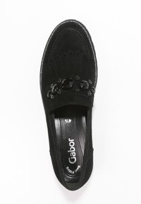 Svart mockaskor med platt sula, prydda med dekorativa svarta stenar längs ovandelen och har en rundad tådesign. Foder med branding.