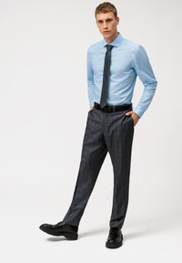 Camicia azzurra chiara, pantaloni a quadri grigio scuro, cintura nera e scarpe nere. Presenta maniche lunghe, colletto e un design slim fit.