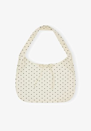 Sac à bandoulière en tissu crème à pois noirs avec un petit nœud noué en détail en haut au centre.
