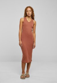 Rochie midi fără mâneci, cu dantelă în relief, de culoare teracotă, cu un decolteu rotunjit și o siluetă ajustată, completată de sandale bej cu talpă plată.