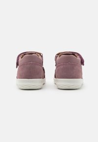 Purple suede shoes with white rubber soles, featuring a back strap for closure, detailed stitching, and subtle textured accents.