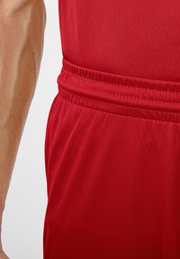 Rote Sportshorts mit elastischem Bund, hergestellt aus glattem, leichtem Stoff und mit subtilen Nähdetails.