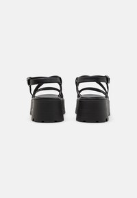Black platform sandals with multiple thin straps and adjustable ankle buckles. The soles are thick and textured for grip.