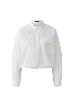 Witte blouse met lange mouwen, knopen, kraag en borstzak geborduurd met gele tekst "aperitivo al mare".