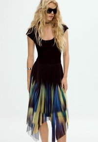 Musthave mustriide mustade lühikeste varrukatega, volditud mitmevärviline seelik, mis üleminek sinisest kollasele, asümmeetrilise hemiga ja läbipaistva pealisega.