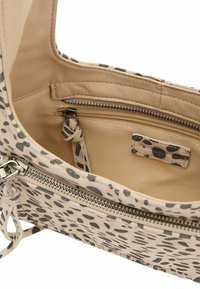 Borsa beige con motivo a macchie nere, dotata di un compartimento con zip e un interno liscio. Il materiale sembra morbido con una finitura elegante.