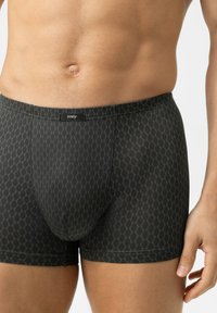 Shorts de boxe noirs avec un motif géométrique dans des tons de vert foncé. Fabriqués en tissu lisse, avec une ceinture logo et une coupe ajustée.