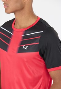 Punainen ja musta urheilupaita, jossa on lyhyet hihat, pyöreä kaula-aukko ja valkoiset korostusraitat hartioilla ja rinnassa. FZ-logo näkyvissä.