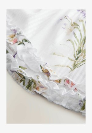 Biely textil s vertikálnymi pruhmi je obohatený o volánový lem zdobený kvetinovými vzormi v odtieňoch ružovej, žltej a zelenej.