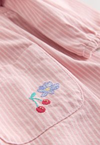 Pink and white striped fabric with a small pocket embroidered with a blue flower and two red cherries.