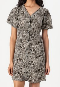 Robe à imprimé léopard en beige et noir avec manches courtes bouffantes, boutonnée à l'avant, et taille cintrée, réalisée en tissu léger.