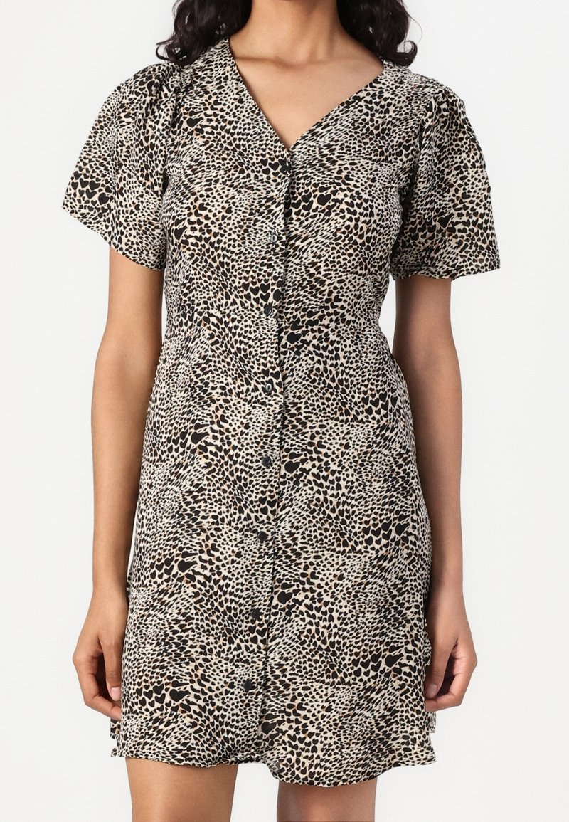 Robe à imprimé léopard en beige et noir avec manches courtes bouffantes, boutonnée à l'avant, et taille cintrée, réalisée en tissu léger.