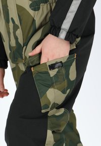 Sneeuwpak met camouflagemotief en zwarte accenten, voorzien van elastische manchetten, een zijzak en oranje stikdetails.