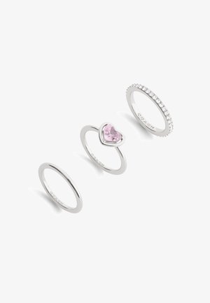 Three silver rings: one with a heart-shaped pink gemstone, one plain band, one adorned with small clear stones along the band.