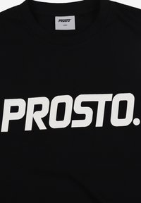 Czarny bawełniany t-shirt z dużym białym napisem "PROSTO." na przodzie, z okrągłym dekoltem i metką wskazującą rozmiar duży.