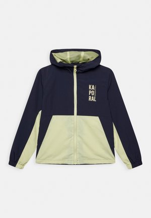 Granatowo-zielona kurtka z kapturem, zapinana na zamek, z elastycznymi mankietami, z nadrukowanym logo w górnej lewej części. Gładka tkanina, lekka konstrukcja.