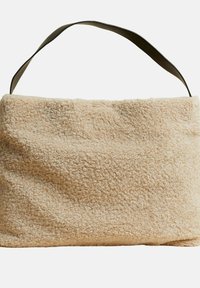 Beige stofpose med tekstur og blød, plyssede overflade samt en kontrasterende mørk rem. Designet er rektangulært med et øverste håndtag.