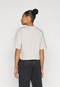 Šviesiai pilka trumpa marškinėlė su trumpomis rankovėmis, pagaminta iš minkštos medžiagos. Turi apvalų kaklo iškirpimą ir laisvą kirpimą, derinama su juodomis kelnėmis.