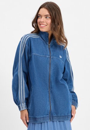 Denim jacket in blue featuring a high collar, zip closure, elastic cuffs, two side pockets, and three white vertical stripes on sleeves.