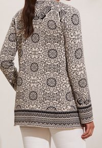 Mönstrad långärmad cardigan i kräm och svart, med intrikata blommiga och fjärilsdesigns, en texturerad finish och kantad fåll.