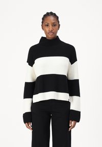 Maglione lavorato a maglia a righe bianche e nere con colletto alto, texture a coste e maniche lunghe. Progettato con una vestibilità rilassata e un'orlo corto.