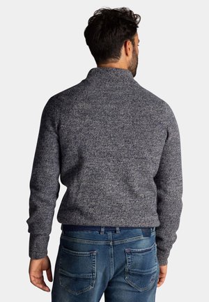 Geverfde gebreide trui in donkergrijs met een hoge kraag, gecombineerd met blauwe denim jeans met achterzakken en een geweven riem.