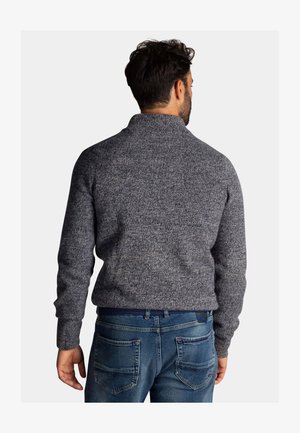 Geverfde gebreide trui in donkergrijs met een hoge kraag, gecombineerd met blauwe denim jeans met achterzakken en een geweven riem.