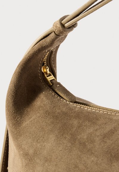 Brown suede handbag featuring a curved shape, gold zipper hardware, and stitched detailing along the opening.