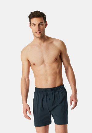 Marineblaue Baumwollboxershorts mit elastischem Bund und Knopfverschluss, die eine lockere Passform und eine glatte Textur bieten.