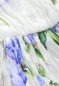 Virágmintás ruha, fodrozott dekoltázzsal, könnyű anyagból készült, fehér színben, kék és zöld árnyalatokkal a virágmintában.