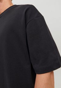 Svart bomull T-shirt med V-ringning, korta ärmar och regular fit. Tyget ser slätt ut med minimal sömmarvid ringningen och ärmarna.