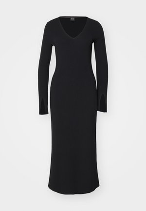 Vestido preto de malha canelada com decote em V, corpete justo, mangas longas e fendas laterais. Com comprimento até ao chão, textura suave e design minimalista.