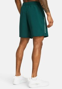 Teal športne kratke hlače z mrežasto teksturo, elastičnim pasom in bočnim razporkom. Na levi nogi je bel logo "UNDER ARMOUR".