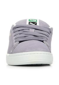 Sneakers in suede lilla con suola in gomma bianca, dotati di lacci piatti e un patch logo verde e nero sulla linguetta. Design minimalista.